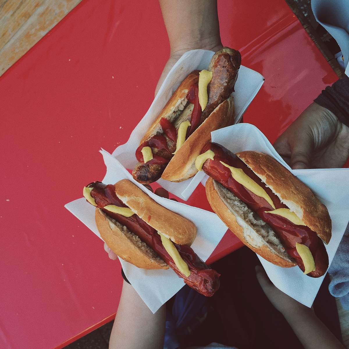 hot dog three persons holding hotdog buns frankfurt